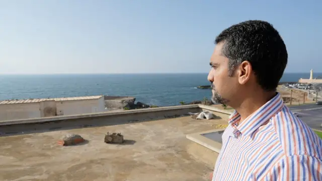 رجل ينظر إلى البحر من سطح أحد المباني 