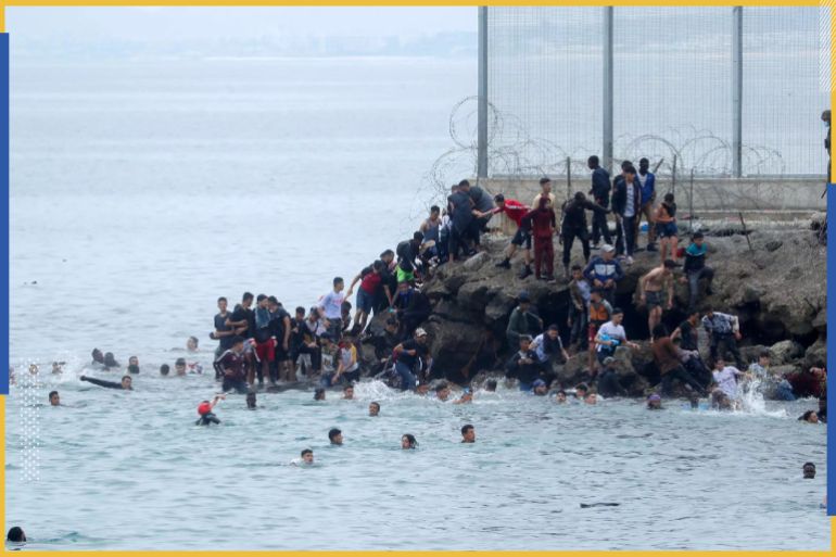 مواطنون مغاربة يقفون بجوار السياج الفاصل بين إسبانيا والمغرب ويسبحون حوله بعد أن سبح آلاف المهاجرين عبر الحدود يوم الاثنين 18 مايو 2021 في سبتة بإسبانيا.